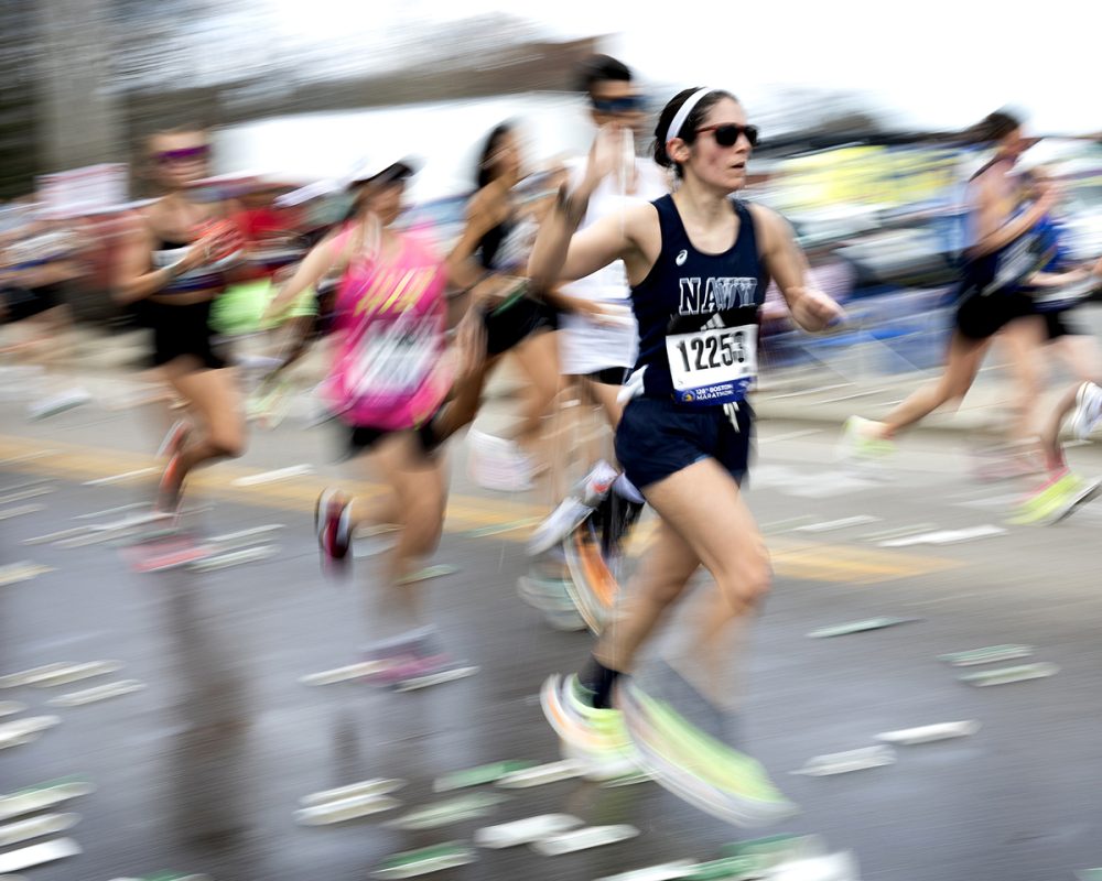 Runner speeding through the Boston Marathon in Framingham captured with motion blur by a Boston Metrowest sports and photojournalism photographer